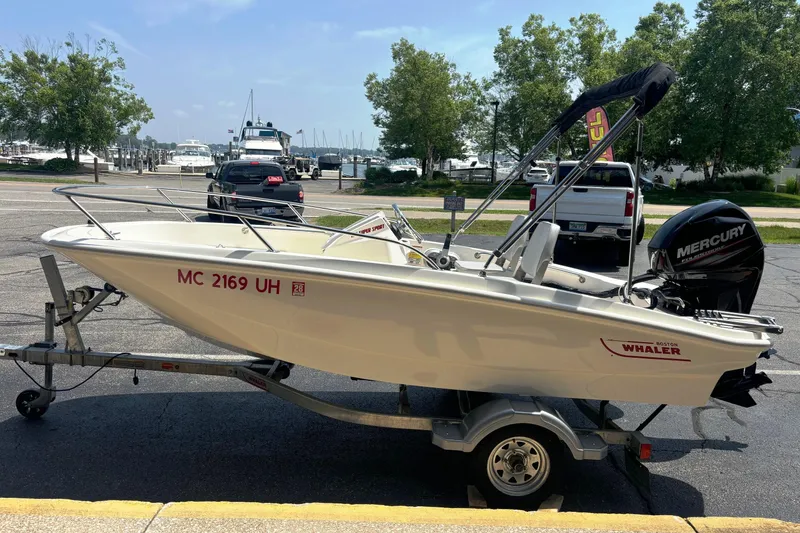 Slide: The Image of 2019 Boston Whaler 130 Super Sport boat on trailer, parked near marina. - 2