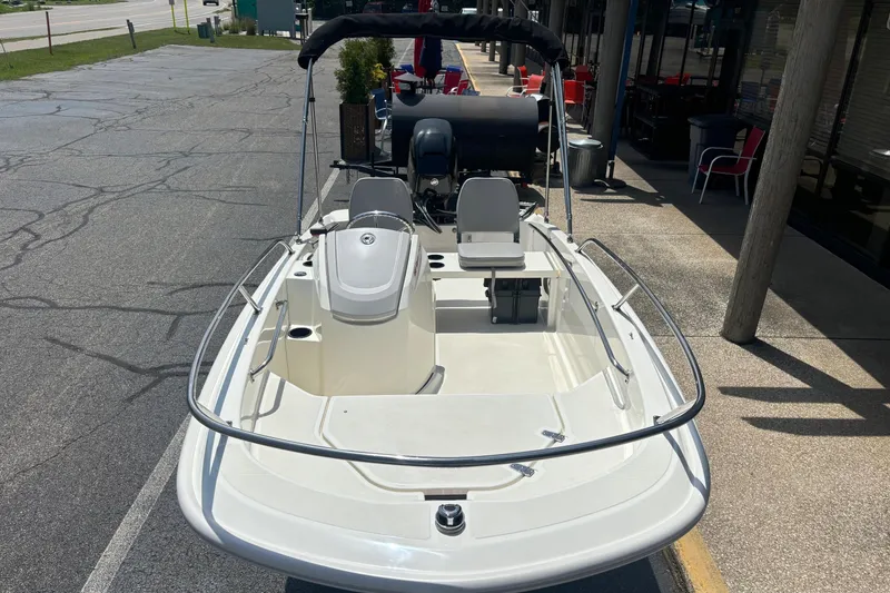 Slide: The Image of 2019 Boston Whaler 130 Super Sport boat parked on pavement, featuring sleek design and seating. - 4