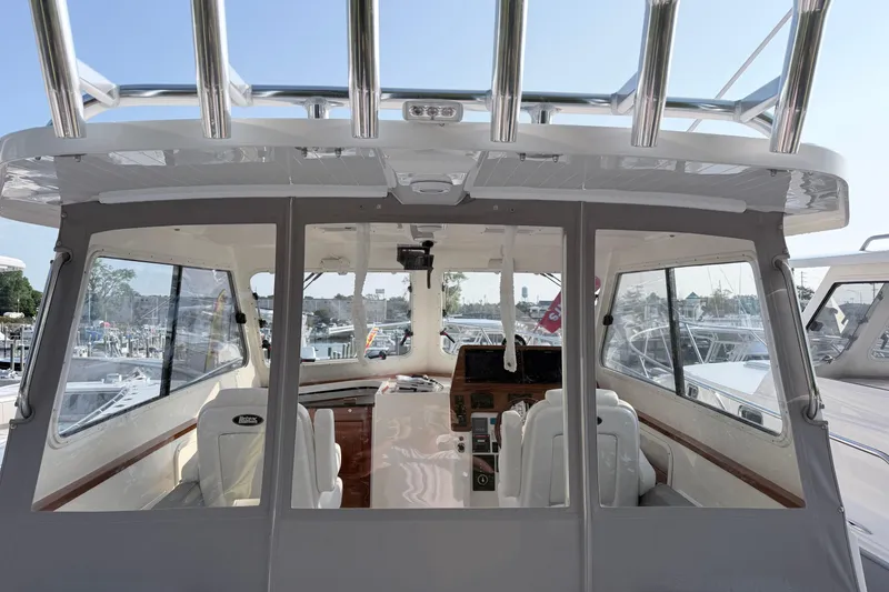 Slide: The Image of 2024 NorthCoast 315 HT boat interior with helm, windows, and seating at a marina. - 7