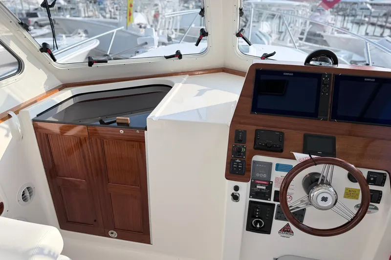 Slide: The Image of 2024 NorthCoast 315 HT helm with dual displays and wooden cabinetry in a marina setting. - 19