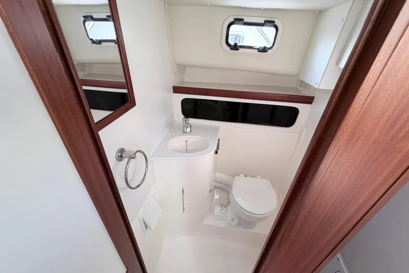 Slide: The Image of 2024 NorthCoast 315 HT boat bathroom with sink, toilet, and window. - 23