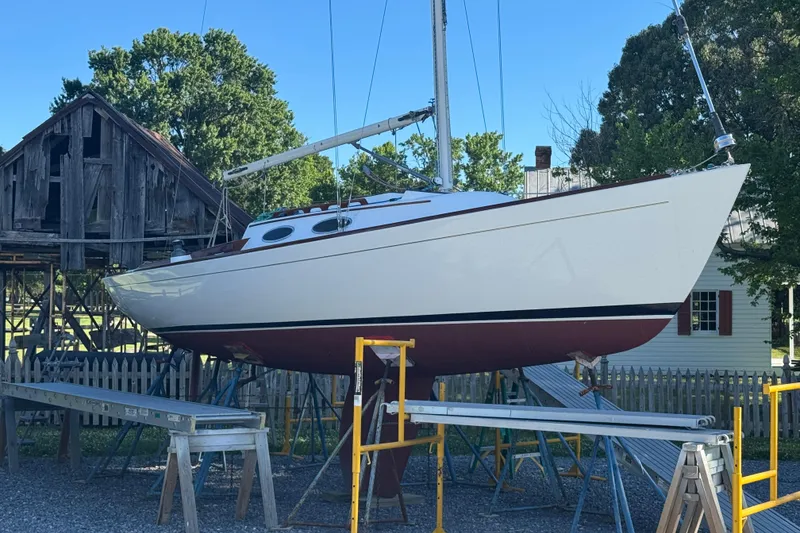 The Image of Alerion 28 sailboat from 1995 on stands near rustic barn and trees. - 0