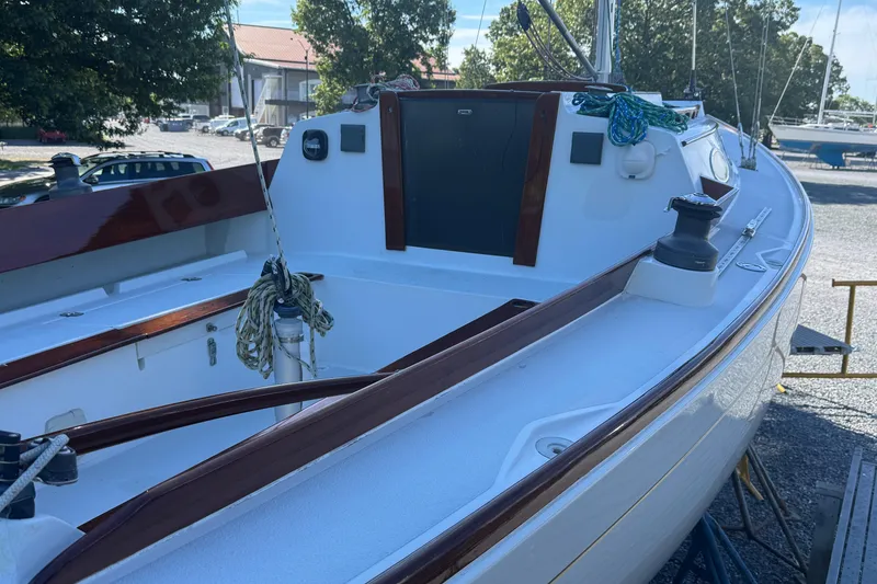 Slide: The Image of 1995 Alerion 28 sailboat with polished wood trim, docked outdoors. - 2