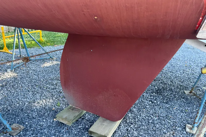 Slide: The Image of Red keel of a 1995 Alerion 28 sailboat on gravel with supports. - 9