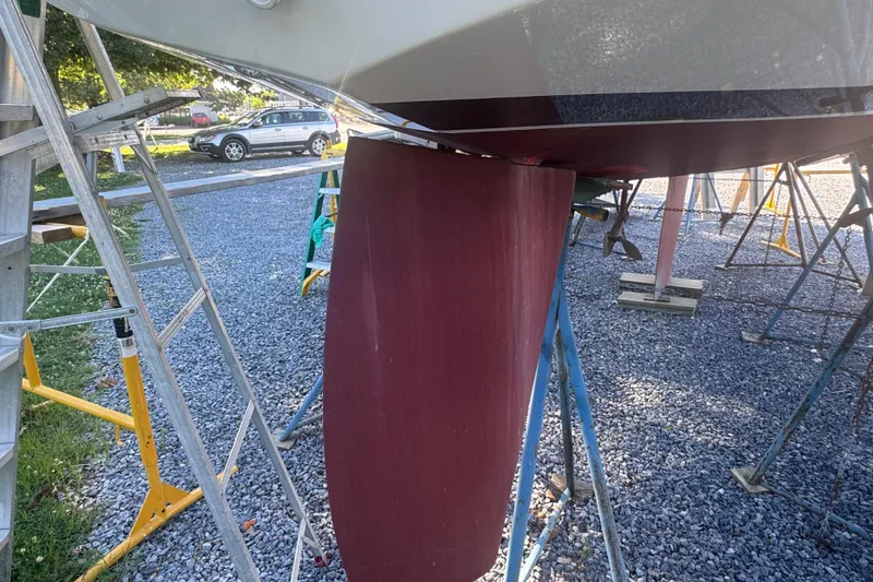 Slide: The Image of Alerion 28 sailboat keel and rudder on stands, gravel yard, 1995 model. - 8