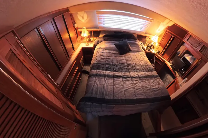 Slide: The Image of Cozy 1988 Sea Ray 415 Aft Cabin bedroom with warm lighting and wooden furnishings. - 49
