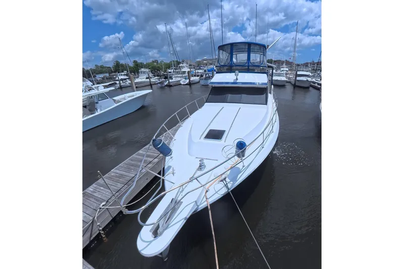 The Image of 1988 Sea Ray 415 Aft Cabin yacht docked at marina under cloudy sky. - 0