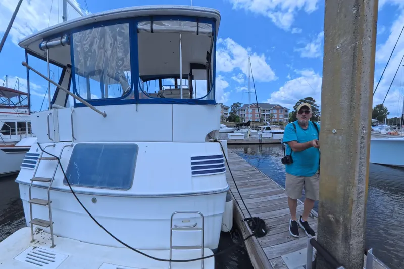 Slide: The Image of 1988 Sea Ray 415 Aft Cabin yacht docked at marina with a person nearby. - 6