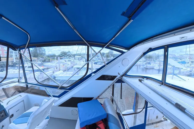 Slide: The Image of Interior view of 1988 Sea Ray 415 Aft Cabin yacht with blue canopy and marina backdrop. - 9