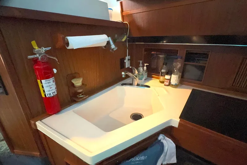 Slide: The Image of 1988 Sea Ray 415 Aft Cabin kitchen sink with fire extinguisher and cleaning supplies. - 43