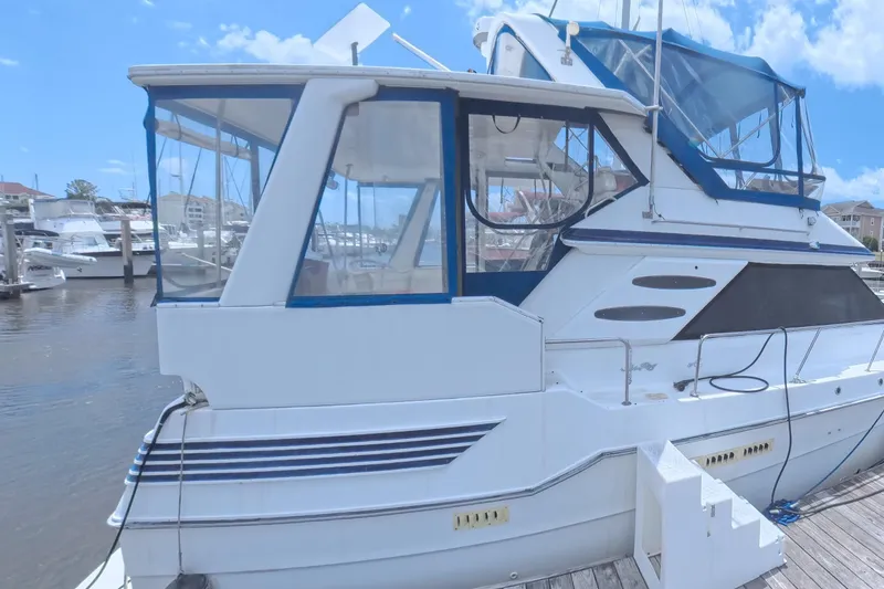 Slide: The Image of 1988 Sea Ray 415 Aft Cabin yacht docked at marina under blue sky. - 2