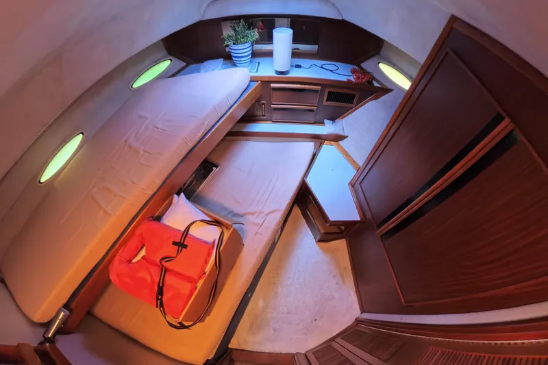 Slide: The Image of 1988 Sea Ray 415 Aft Cabin interior with bed, storage, and portholes. - 57