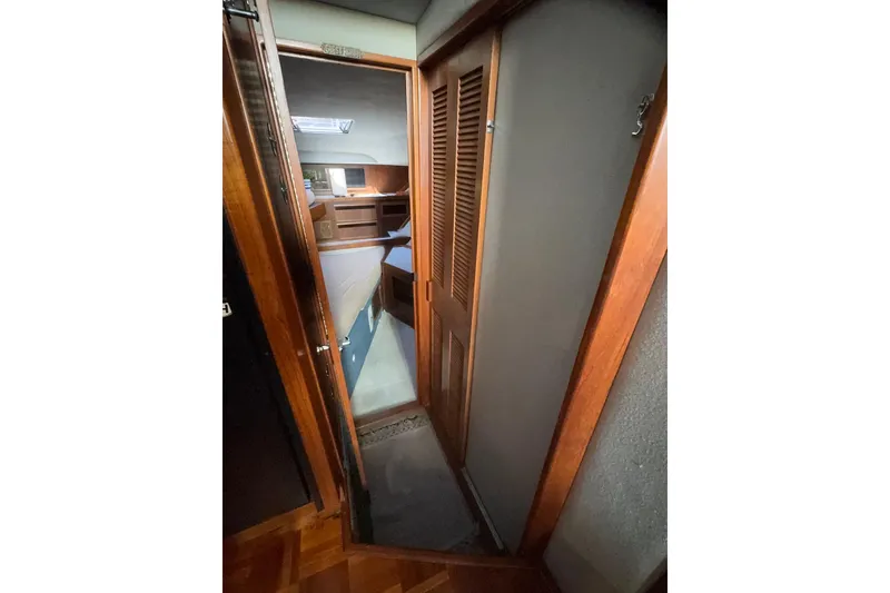 Slide: The Image of 1988 Sea Ray 415 Aft Cabin interior hallway with wooden doors and cozy bedroom view. - 54