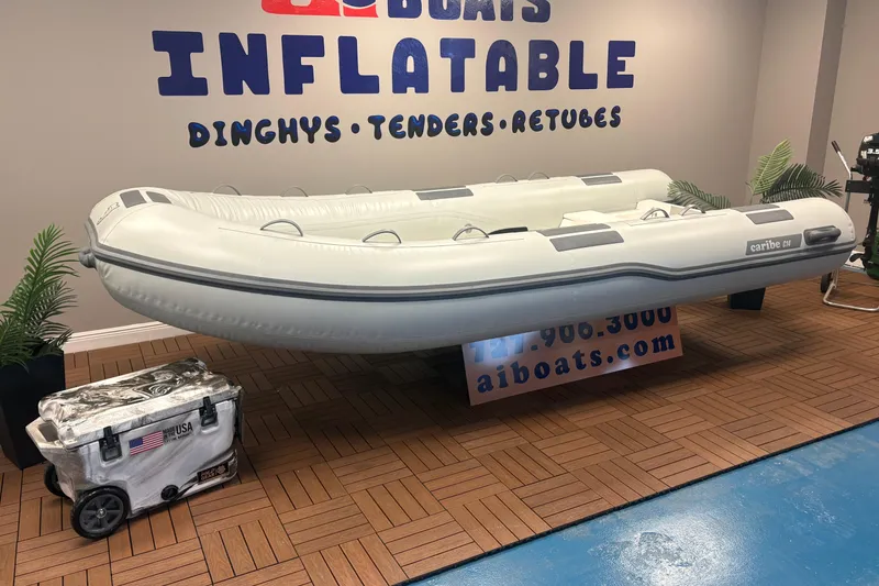 Slide: The Image of Inflatable Caribe C-14 boat displayed indoors, with promotional signage and decorative plants. - 2