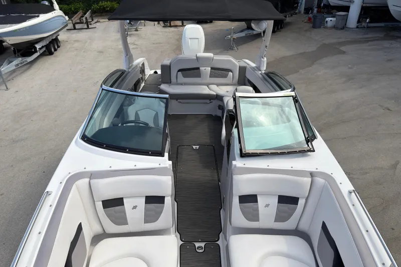 Slide: The Image of 2018 Four Winns HD270 OB boat interior with seating and windshield, docked outdoors. - 13