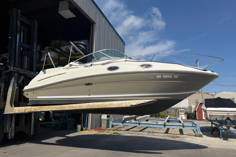 Slide: The Image of 2006 Sea Ray 240 Sundancer boat lifted outside a storage facility under a clear blue sky. - 4