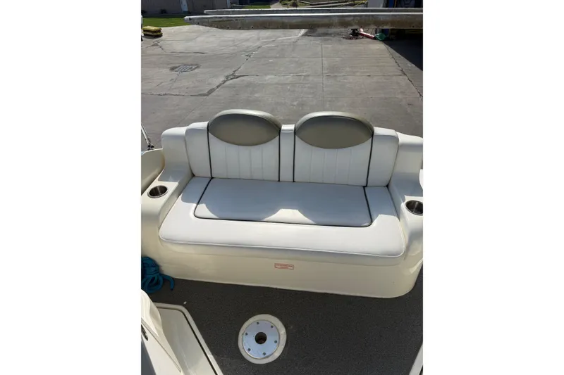 Slide: The Image of 2006 Sea Ray 240 Sundancer boat seating area with cup holders and cushioned bench. - 18