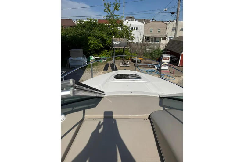 Slide: The Image of 2006 Sea Ray 240 Sundancer boat in a yard, surrounded by equipment and greenery. - 17