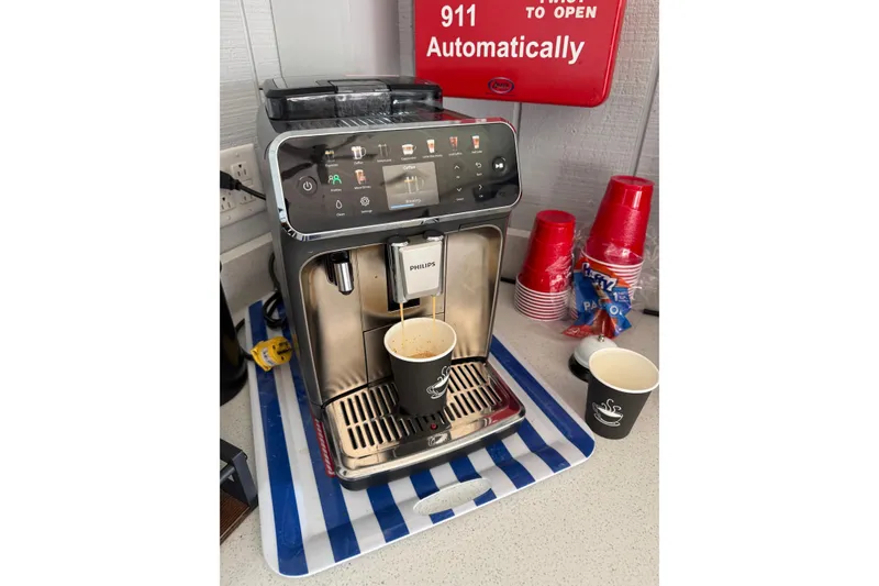 Slide: The Image of Philips coffee machine brewing coffee, surrounded by red cups and snacks on a countertop. - 5