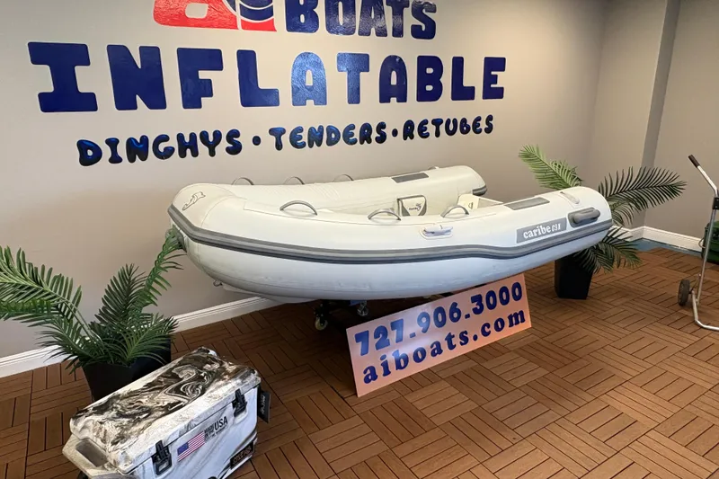 Slide: The Image of Inflatable Caribe C-9X boat displayed indoors with promotional signage. - 2