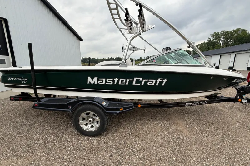 The Image of 2005 MasterCraft ProStar 197 boat on trailer, parked outdoors near a building. - 1