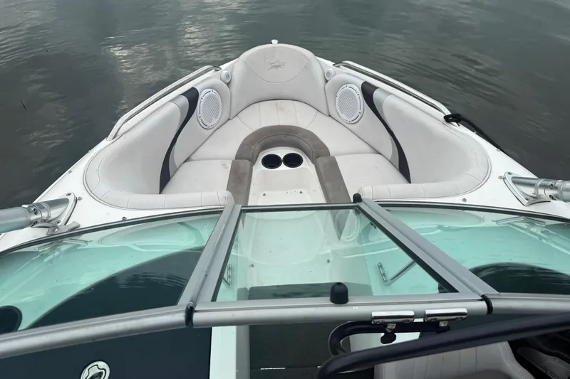 Slide: The Image of 2005 MasterCraft ProStar 197 boat interior with white seating and speakers on a calm lake. - 13