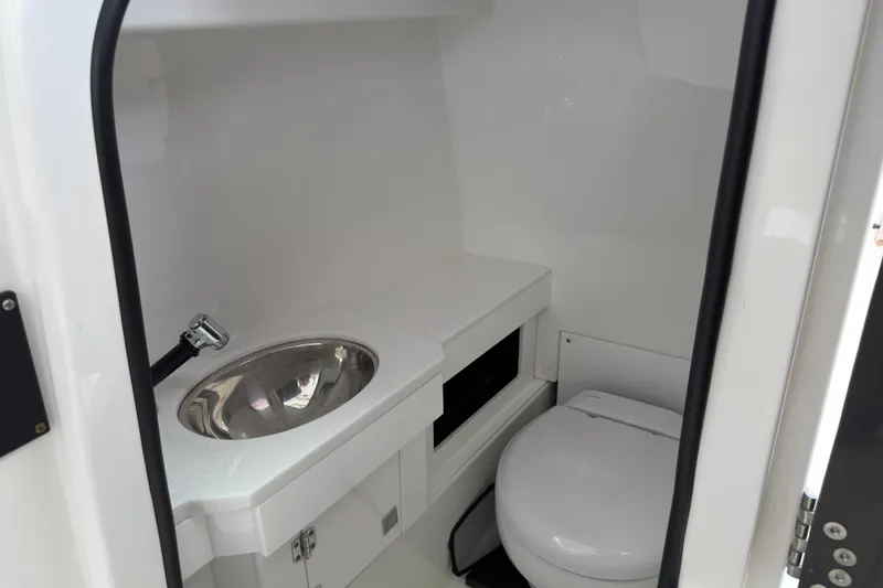Slide: The Image of 2023 Blackfin 272 DC boat interior with sink and toilet in compact bathroom. - 13