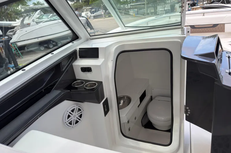 Slide: The Image of Interior view of 2023 Blackfin 272 DC boat featuring a compact marine toilet. - 12