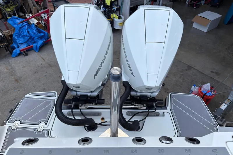 Slide: The Image of 2023 Blackfin 272 DC boat with dual Mercury outboard engines in a workshop setting. - 20