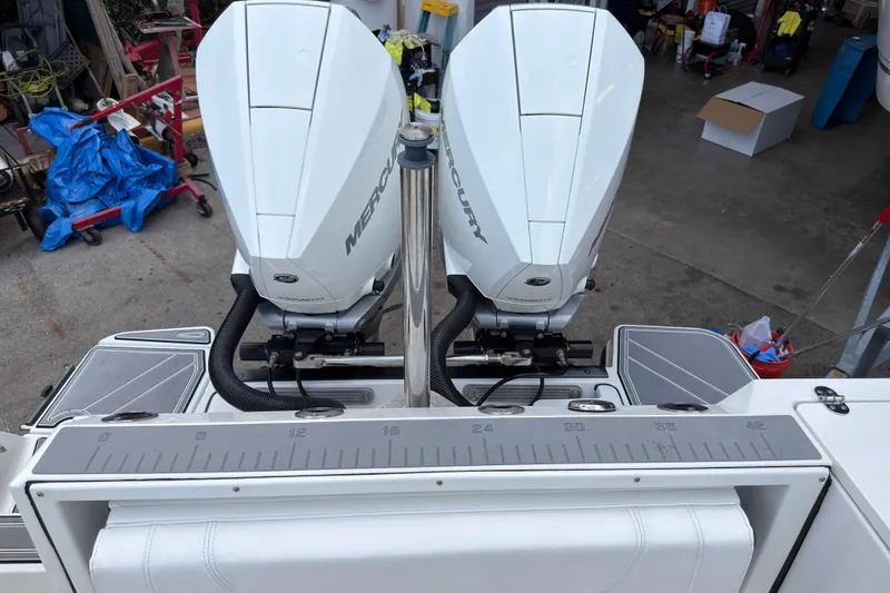 Slide: The Image of 2023 Blackfin 272 DC boat with dual Mercury outboard engines in a garage setting. - 21