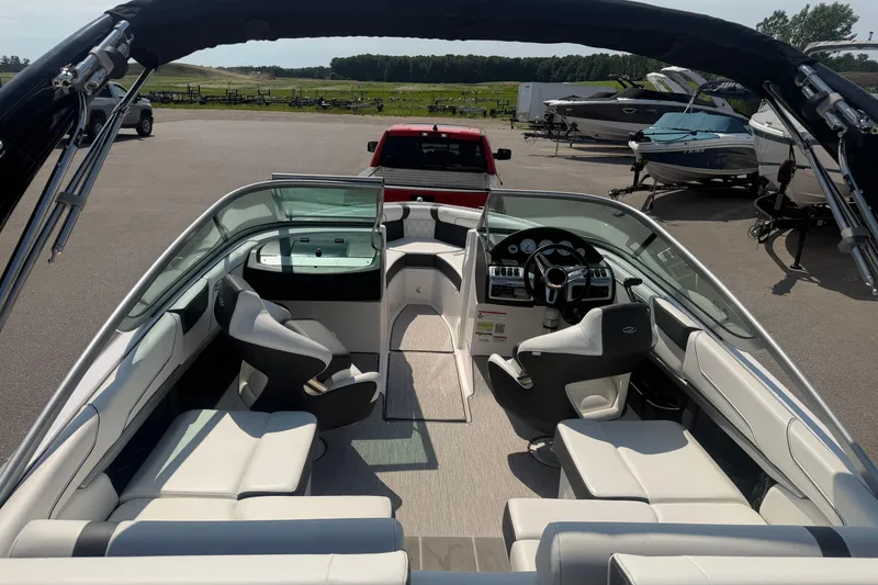 Slide: The Image of 2019 Regal 2100 boat interior with seating and steering wheel, parked outdoors. - 29