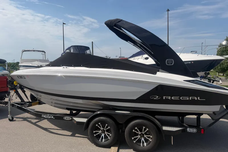 Slide: The Image of 2019 Regal 2100 boat on trailer, sleek design, black and white color scheme, parked outdoors. - 28