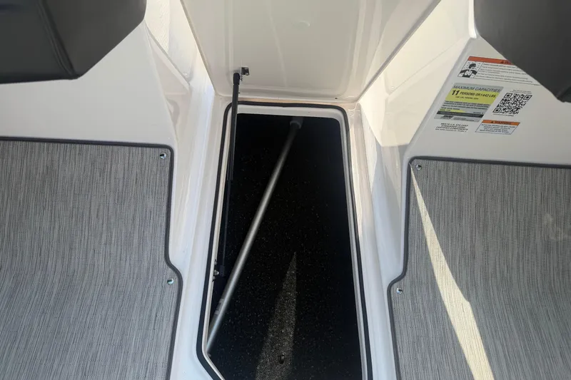 Slide: The Image of 2019 Regal 2100 boat storage compartment with open hatch and safety labels. - 23