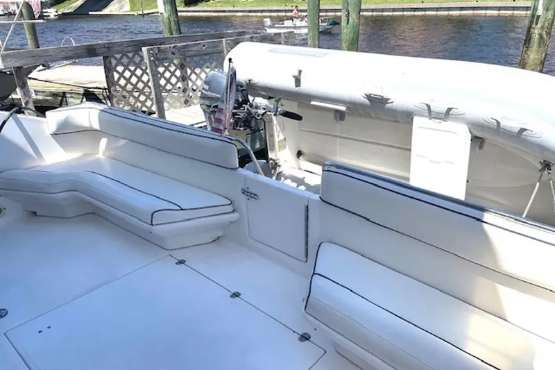 Slide: The Image of Spacious deck of 1996 Sea Ray 500 Sedan Bridge with white seating and docked inflatable boat. - 29