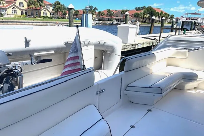 Slide: The Image of 1996 Sea Ray 500 Sedan Bridge yacht with white seating and American flag in marina. - 27