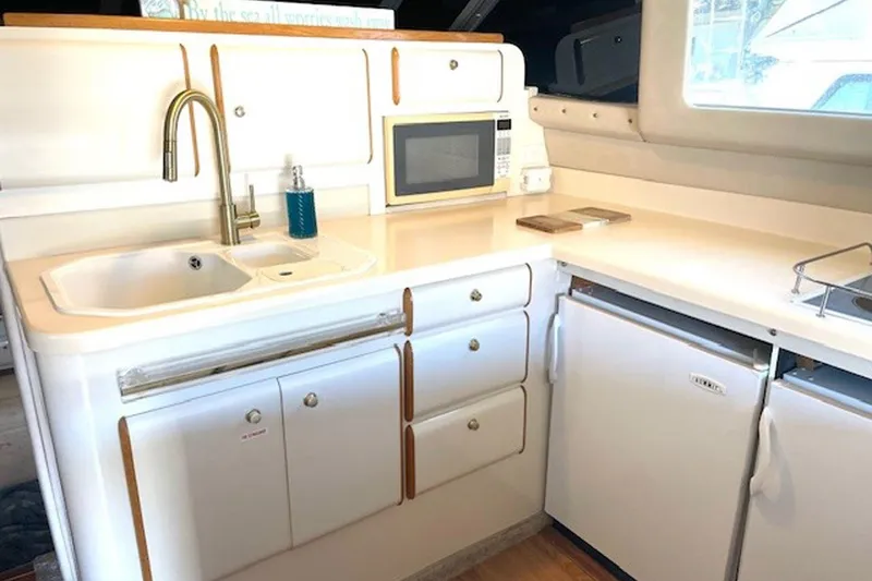 Slide: The Image of 1996 Sea Ray 500 Sedan Bridge kitchen with sink, microwave, and refrigerator. - 17