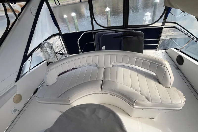 Slide: The Image of 1996 Sea Ray 500 Sedan Bridge interior with curved white seating and waterfront view. - 24