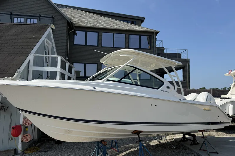 Slide: The Image of 2027 Pursuit DC 266 Dual Console boat displayed outdoors near a modern building. - 1