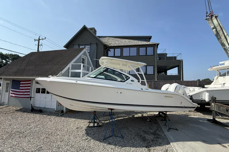 The Image of 2027 Pursuit DC 266 Dual Console boat displayed outdoors near a building. - 0