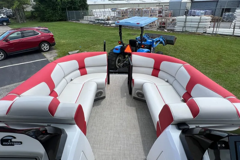 Slide: The Image of 2020 Monterra Surf boat interior with red and white seating, parked near a tractor. - 14