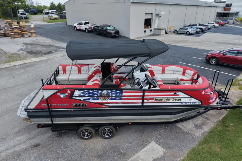 Slide: The Image of 2020 Monterra Surf boat with patriotic design, parked on a trailer in an industrial area. - 21