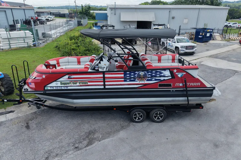 Slide: The Image of Red Monterra Surf 2020 boat with patriotic design, parked on a trailer in an industrial area. - 5