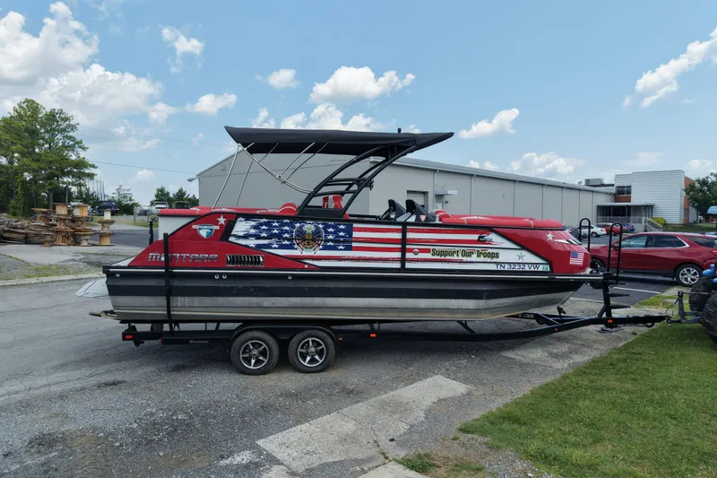 Slide: The Image of 2020 Monterra Surf boat with patriotic design on trailer, parked outdoors. - 22