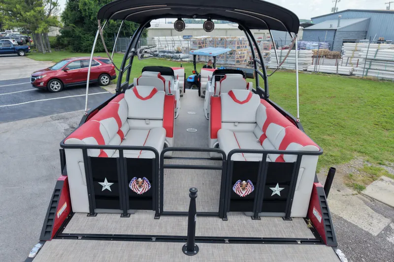 Slide: The Image of 2020 Monterra Surf boat with red and gray seating, parked on grass near a red SUV. - 9
