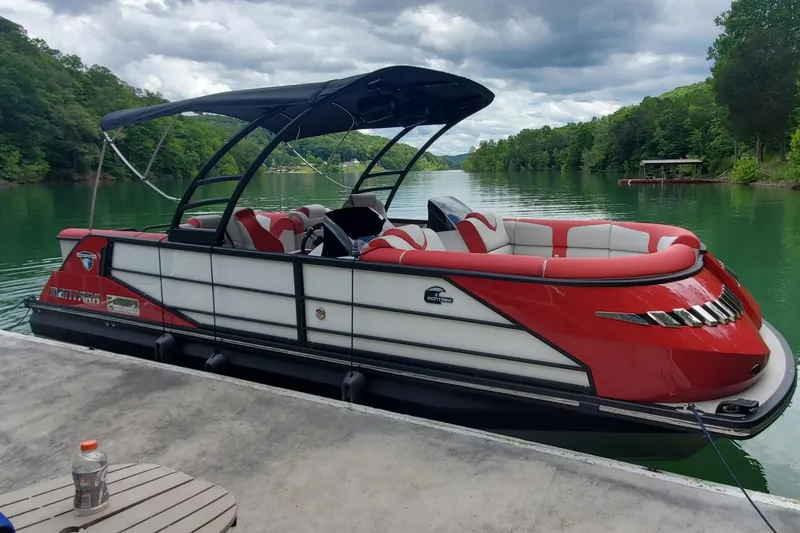 Slide: The Image of 2021 Montara Surf Boss boat docked on a serene lake with lush green surroundings. - 23