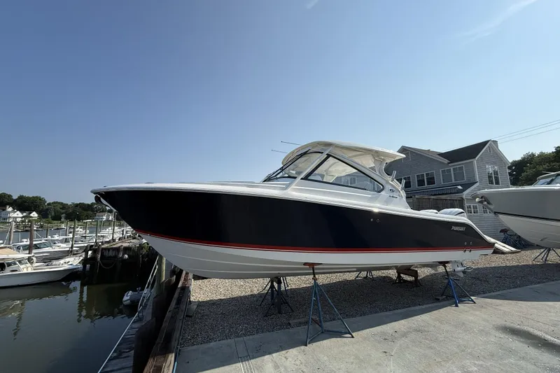 Slide: The Image of 2027 Pursuit DC 286 Dual Console boat docked near marina under clear sky. - 3