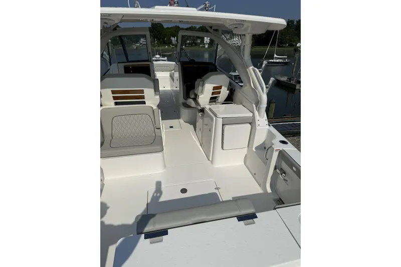 Slide: The Image of 2027 Pursuit DC 286 Dual Console boat interior with seating and storage, docked by the water. - 5