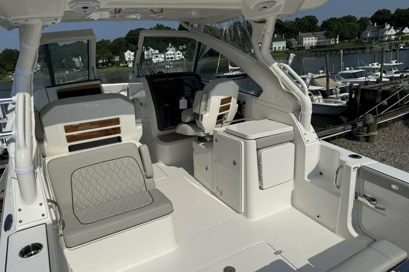 Slide: The Image of 2027 Pursuit DC 286 Dual Console boat interior with seating and helm, docked at marina. - 6