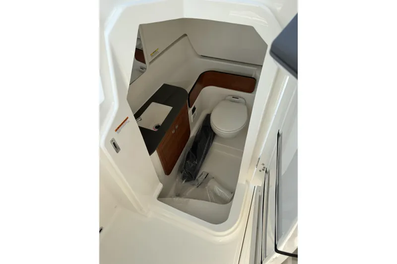 Slide: The Image of 2027 Pursuit DC 286 Dual Console boat interior with compact bathroom and sink. - 14