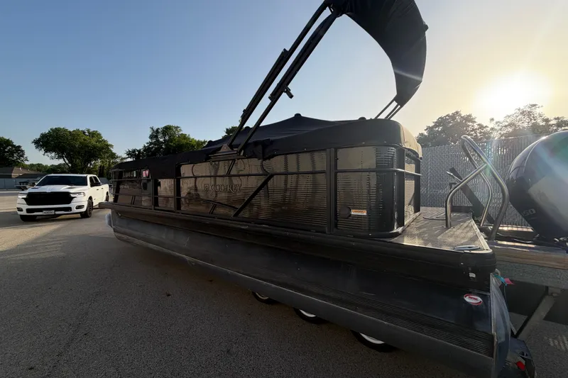 Slide: The Image of 2023 Godfrey Sweetwater 2286 C pontoon boat with canopy, parked beside a white vehicle. - 4